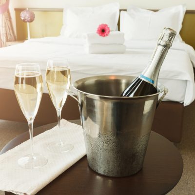 Two glasses of and champagne in ice bucket in hotel. Romance, room service, relax concept, copy space